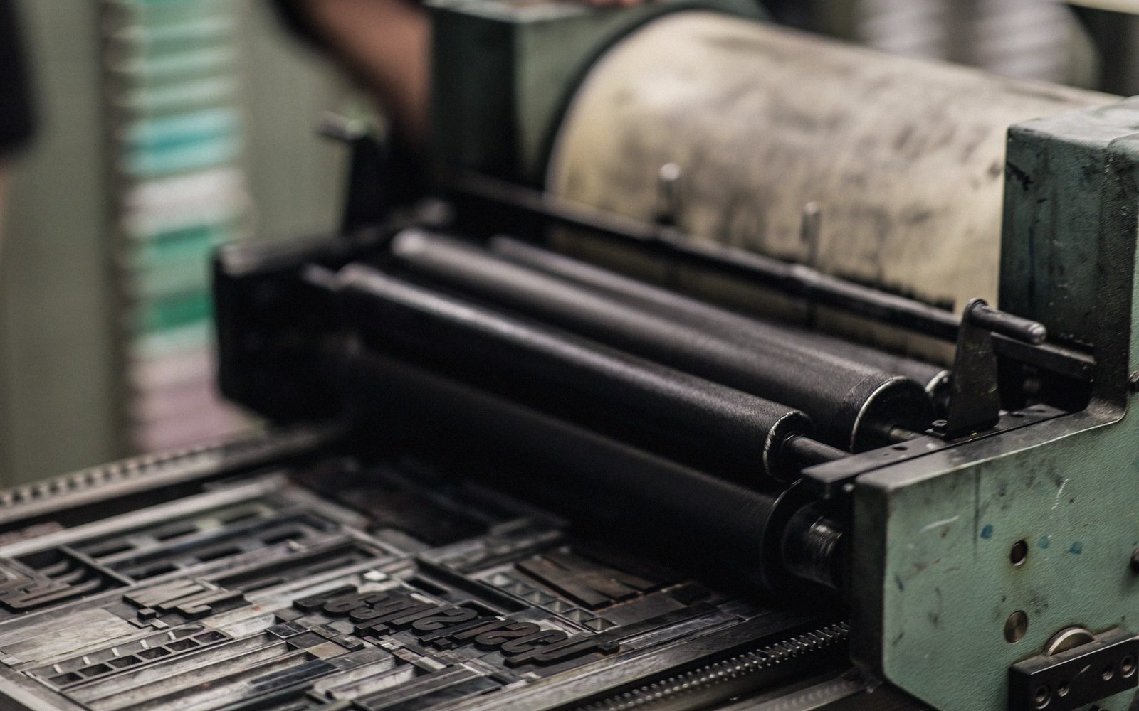 Inked rollers on a letterpress machine positioned above metal type blocks